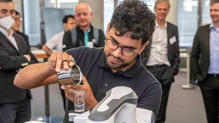 Dr. Luis Figueredo aus dem Robotikinstitut MIRMI der TU München (TUM) bringt einem Roboter bei, ein mit Wasser gefülltes Glas zu transportieren. Foto: © Wolfgang Maria Weber / TUM