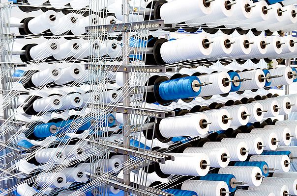 Bei der Herstellung von Textilien werden zahllose Garnrollen verbraucht. (©: richterfoto/iStockphoto)