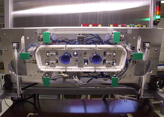 The bonding unit for the assembly of convertible tops: The tailgate is placed in the upper die, which is fastened to a large flap. The assembly is performed by pneumatic cylinders.